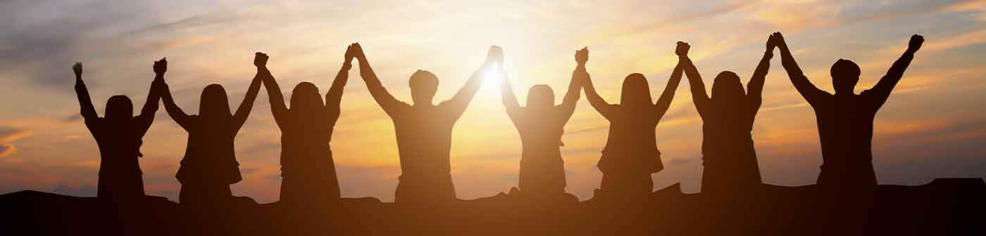sunset silhouette of teammates holding hands up