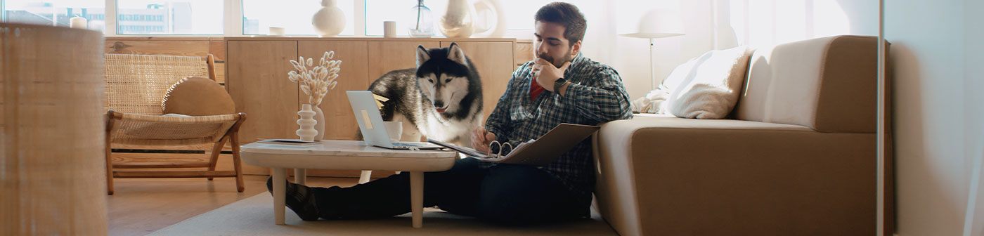 man, laptop and husky working in his living room