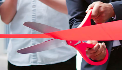 giant scissors cutting a red ribbon
